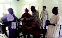 The Kayes Regional Director of Health gives a computer to a DHIS 2 user at a community health center. Purchases of computers and other equipment in Mali were supported by USAID/ASSIST (an HIS partner in Kayes).